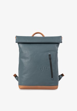 Zaino in materiale impermeabile blu scuro con chiusura roll-top, dettagli in pelle marrone chiaro, tasca laterale con zip e spallacci regolabili.