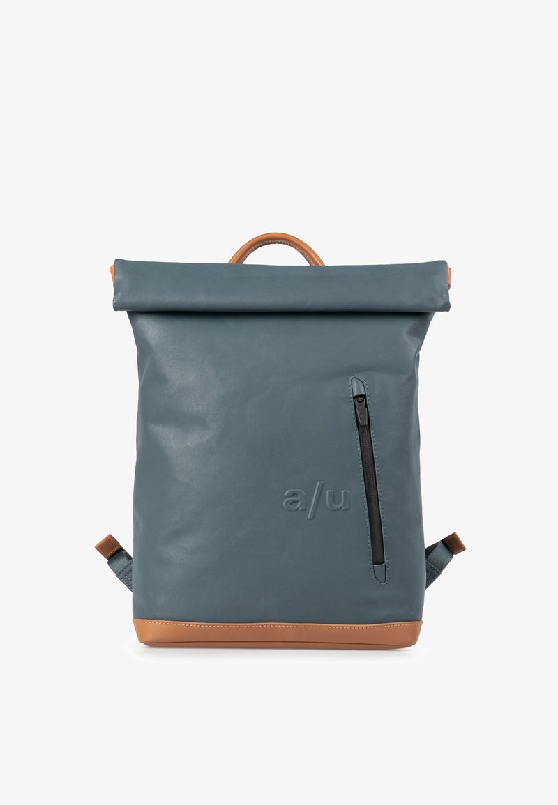 Rugzak in donkerblauw waterdicht materiaal met een rol-top sluiting, tan leren accenten, een zijvak met rits en verstelbare schouderbanden.