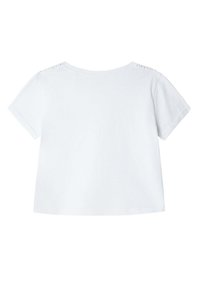 Camiseta blanca de manga corta con un corte holgado, cuello redondo y botones decorativos en los hombros. Material de algodón suave.