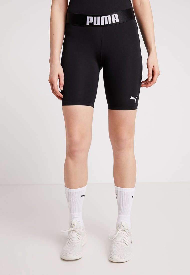 Czarne spodenki sportowe z rozciągliwego materiału z grubym paskiem w talii, na którym znajduje się logo "PUMA". Gładka faktura, dopasowany krój, długość do połowy uda.