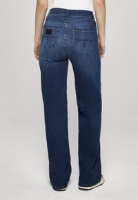 Temno modre kavbojke iz jeansa z ravnim krojem hlačnic, z zadnjimi žepi in logotipom. Gladek teksturni videz z minimalnimi izbledelimi detajli.