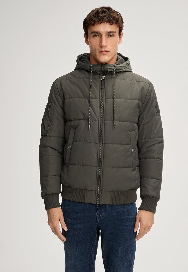 Giubbotto puffer khaki con cappuccio aderente, chiusura frontale con zip, polsini a coste e due tasche laterali. Presenta un design trapuntato e cordini regolabili.