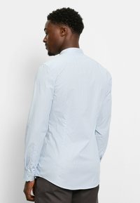 Himmelblaues Langarmhemd mit feinem Nadelstreifenmuster, mit Knopfmanschetten und kleinem Kragen. Glatte Textur und taillierte Passform.