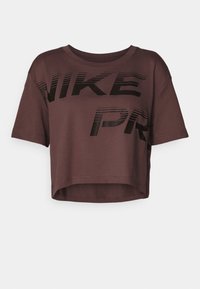 Ruskea lyhythihainen croppi-t-paita, joka on valmistettu pehmeästä kankaasta. Esiintyy voimakas musta "NIKE PRO" -logo etuosassa.