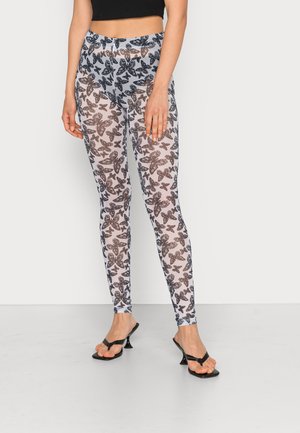 Leggings com padrão de borboleta apresentando uma base branca transparente com designs em preto e castanho. Ajuste slim com cintura alta e comprimento até o tornozelo.