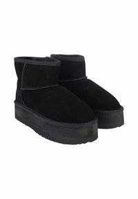Stivali ankle in suede neri con punta arrotondata, suola piatta e dettagli cuciti lungo le cuciture.