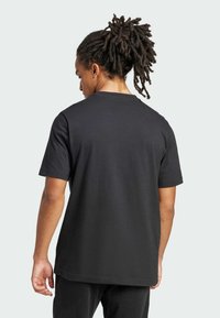 Μαύρο βαμβακερό t-shirt με κοντό μανίκι, που διαθέτει στρογγυλή λαιμόκοψη και άνετη γραμμή. Απαλή υφή, χωρίς ορατά σχέδια ή λεπτομέρειες.