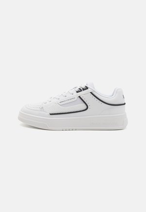 Sneakers atletici bianchi con un design testurizzato, caratterizzati da una striscia di accento grigia, punta rotonda e un logo del marchio prominente sul lato e sul tallone.