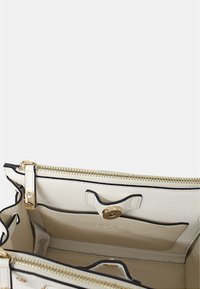 Borsa bianca con dettagli in oro, dotata di chiusura a zip, tasche interne e bordi a contrasto neri.