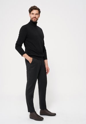 Czarny sweter z golfem, dopasowane czarne spodnie oraz ciemnobrązowe buty sznurowane. Gładka faktura i minimalistyczny design.