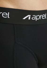 Schwarze Boxer-Shorts mit einem breiten elastischen Bund mit weißem "aprel"-Logo. Glattes Material mit verstärkten Nähten für Langlebigkeit.