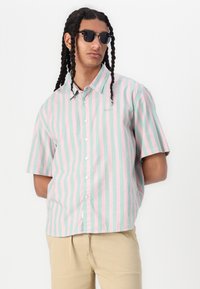 Chemise à manches courtes à boutons en rayures verticales rose et menthe, avec un col classique et un logo subtil sur la poitrine.