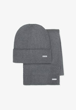 Conjunto de gorro y bufanda gris de punto con textura acanalada. Ambas piezas tienen un puño doblado y una pequeña etiqueta de la marca. Material suave.