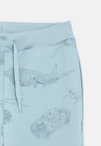 Light blue sweatpants featuring detailed, line-drawn illustrations of cars and aircraft, with a ribbed waistband and drawstring.