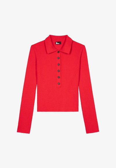 Rød ribbet langærmet top med kraveudskæring og seks sorte knapper foran, med detaljer på sidel paneler og kort længde.