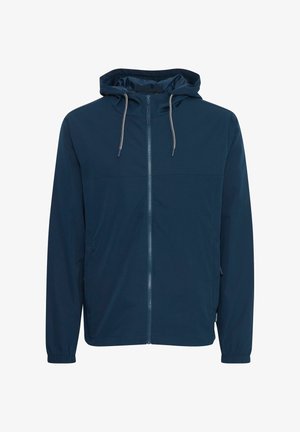 Tumedast sinise kapuutsiga jakk, mis on valmistatud siledast kangast. Omab esimest tõmblukk, reguleeritavat kapuutsi ja küljetaskuid koos elastsete mansettidega.