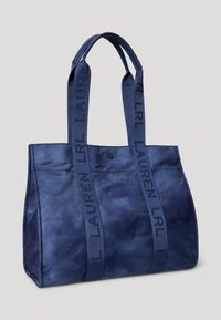 Mörkblå tygväska med slät yta, försedda med texturerade handtag och varumärkeslogotyp. Öppen topp och strukturerad design för rymlig förvaring.