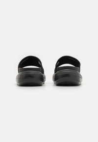 Sandali casual neri con suola ammortizzata, apertura sul retro e cinture elastiche. Accenti neri testurizzati sulla ammortizzazione per una presa e un comfort migliori.