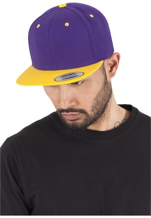Lila snapback sapka sárga karimával. Lapos karimával, struktúrált tervezéssel és kontrasztos hímzett szellőzőnyílásokkal rendelkezik.