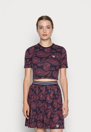 Cropped top blu navy e gonna plissettata coordinata con motivo paisley rosso. Include un logo di marca e dettaglio a righe in vita.