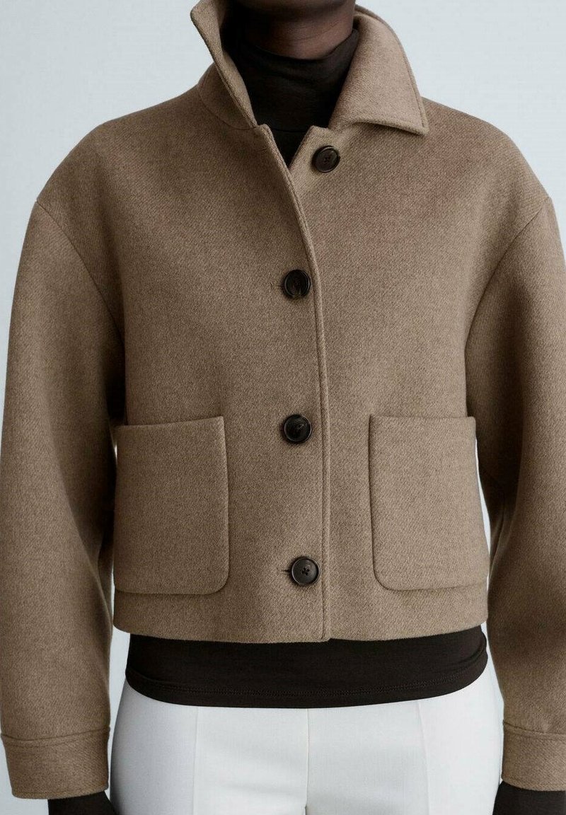 Veste courte en mélange de laine marron avec un col, comportant trois boutons noirs et deux poches avant. Texture lisse et coupe décontractée.