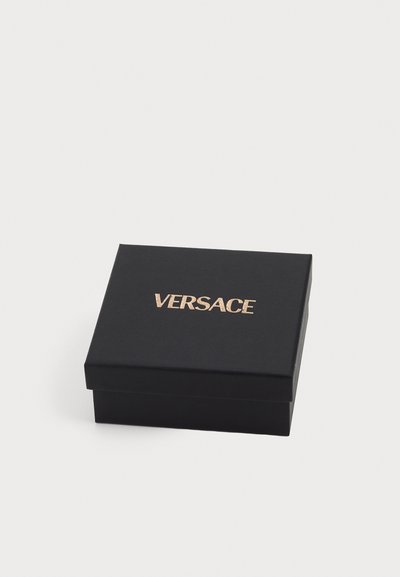 Juodas stačiakampis dovanų dėžutė su matinio paviršiaus tekstūra, ant viršaus pavaizduotas auksu iškilęs "VERSACE" logotipas.