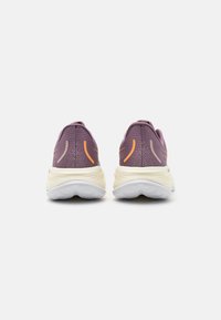 Zapatillas deportivas moradas con una parte superior texturizada, que presentan acentos en naranja y gris en el talón y una suela blanca acolchada.