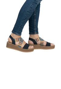 Wedge sandals with a braided jute heel, featuring black straps and a colorful geometric pattern across the center.