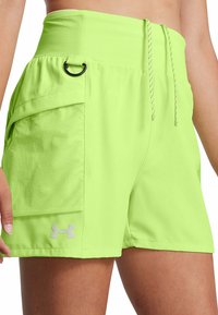 Pantalones cortos deportivos de color verde lima con una cinturilla alta, bolsillo lateral, cordón de ajuste y logotipo reflectante en el dobladillo. Fabricados en un material ligero y texturizado.