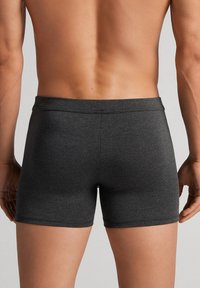 Dunkelgraue Boxershorts aus glattem, elastischem Gewebe. Sie verfügen über ein nahtloses Bündchen und ein tailliertes Design und zeigen eine schlichte Textur ohne Muster.