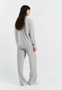 Graues Strick-Loungewear-Set mit einer lockeren Passform, bestehend aus einem Sweatshirt und weit geschnittenen Hosen. Weicher Stoff, gerippte Bündchen und ein minimalistisches Design.