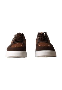Paire de baskets marron à lacets avec semelles blanches et petits clous ronds à l'avant et sur les côtés, vues de face.