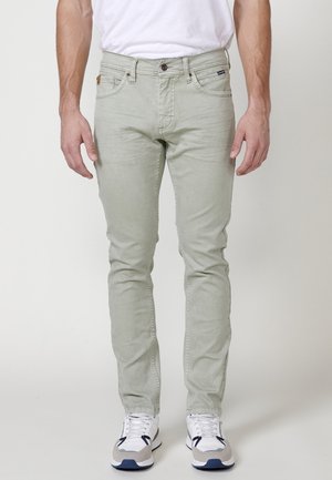 Jeans verde claro con un corte slim, diseño de cinco bolsillos y cierre de botón. La tela tiene una textura suave con un ligero desgaste.