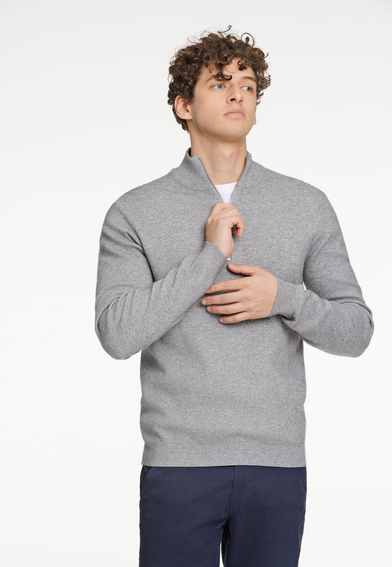 Maglione grigio a maglia con colletto alto e design a mezza zip. Caratterizzato da polsini e orlo a coste, abbinato a pantaloni blu scuro.