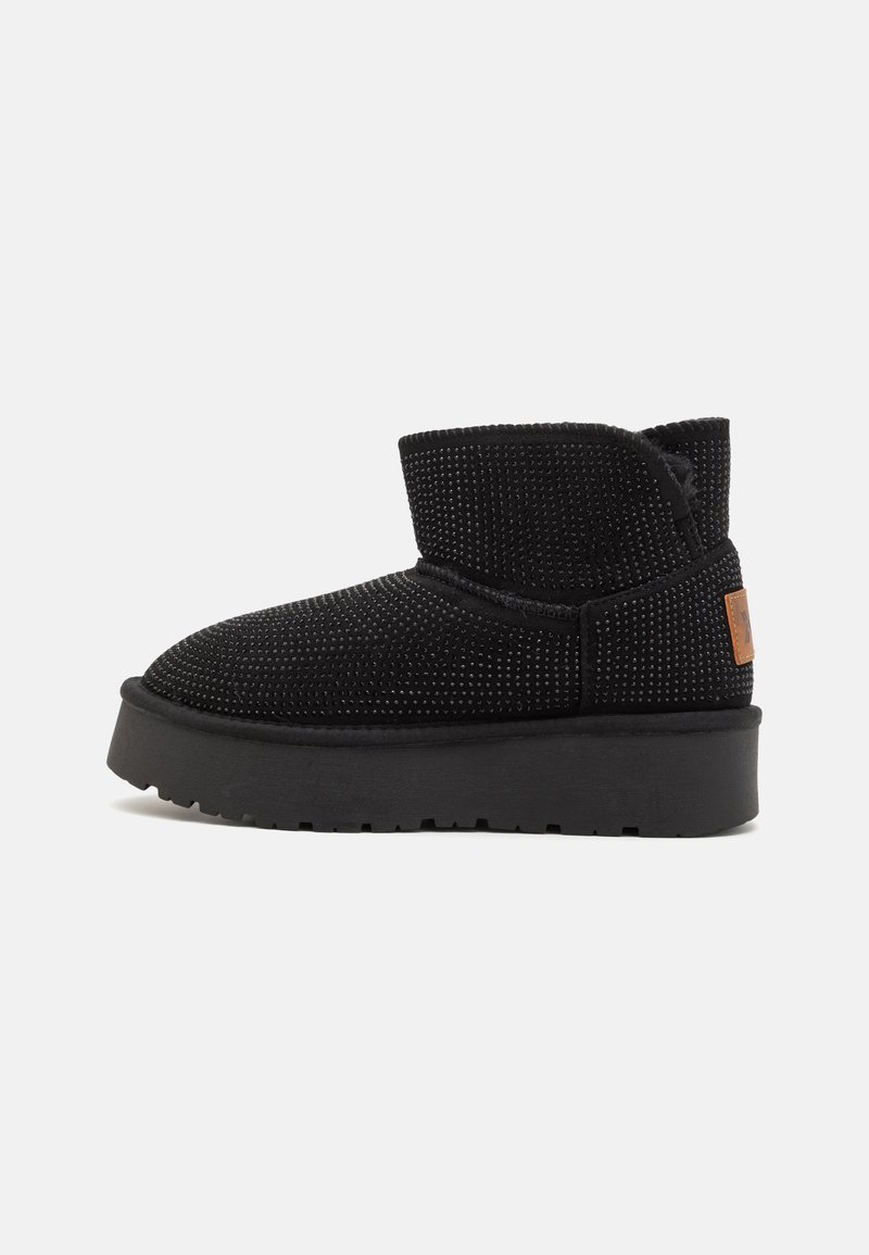 Black ankle boot made of textured fabric with a rounded toe, elastic collar, and a flat rubber sole with a slight platform height.