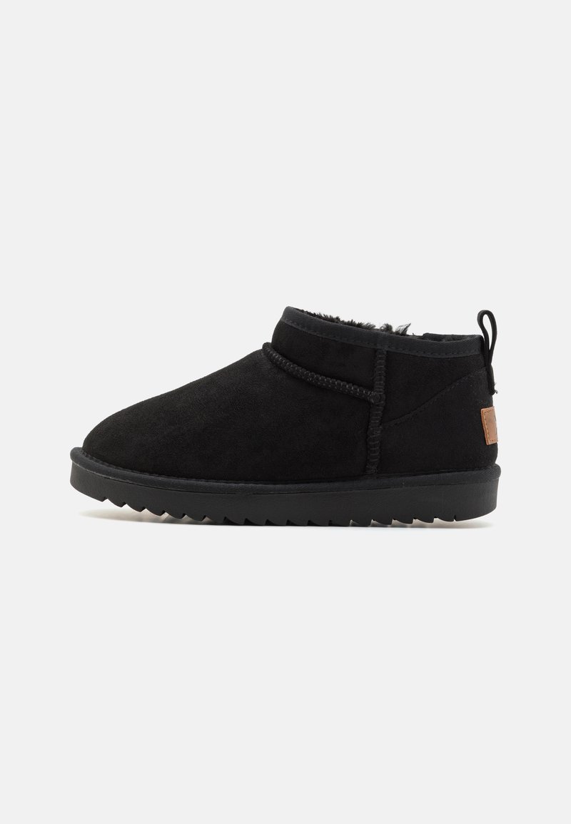 Botas de tobillo de ante negro con puntera redondeada, detalles de costura y una suela texturizada. Presenta una pequeña pestaña trasera y un parche de acento en contraste.