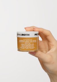 Pumpkin Enzyme Mask i en klar glasburk, fylld med orangebrun kräm. Har ett vitt lock med svart text som detaljerar produktinformationen.