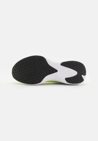 Suela de goma negra con patrón de agarre texturizado, que presenta una entresuela blanca y acentos verdes, diseñada para la estabilidad en calzado deportivo.