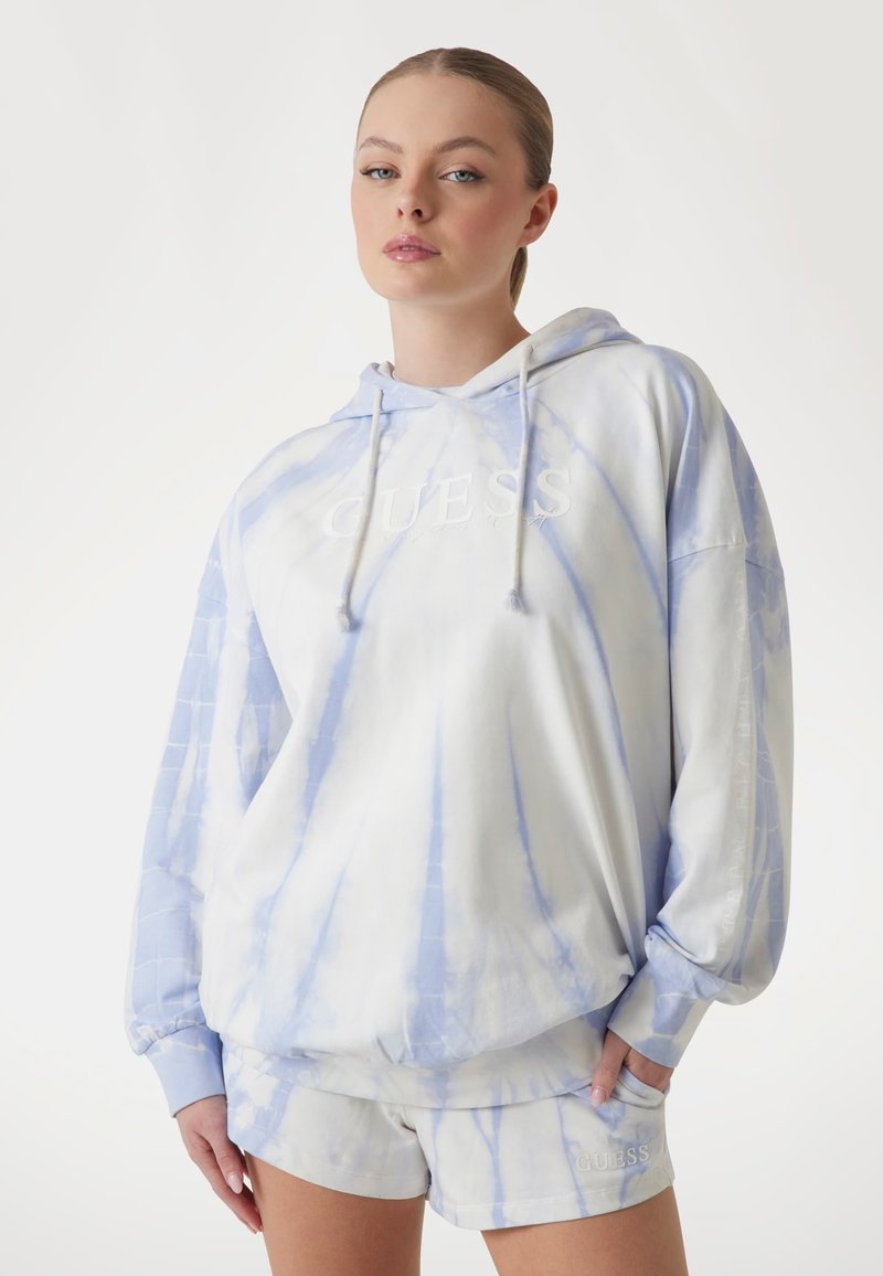 Svijetloplavi i bijeli hoodie s tie-dye uzorkom, opuštenog kroja, s vezanom oznakom, kapuljačom s vezicom i rebrastim rukavima. Uparen s odgovarajućim šortsevima.