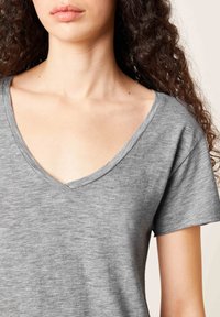 Pilkos spalvos trumpas rankovės marškinėliai su giliu V formos kaklu. Pagaminta iš minkštos, tekstūruotos medžiagos. Turi laisvą kirpimą ir subtilų šviesiai pilką raštą.