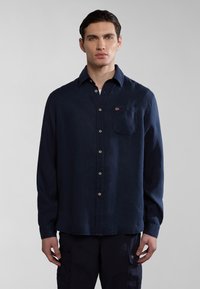 Camicia a maniche lunghe blu navy realizzata in tessuto con taschino sul lato sinistro del petto. Presenta una chiusura con bottoni e un piccolo logo ricamato.