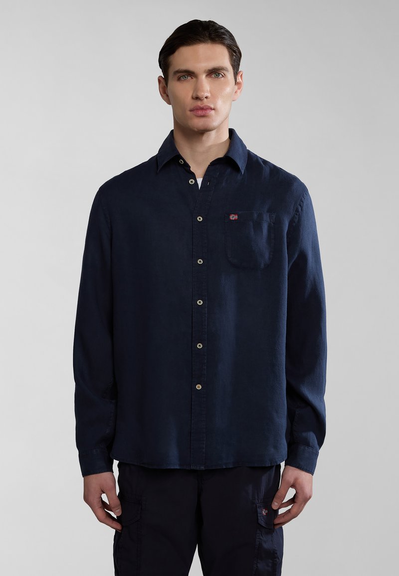 Camicia a maniche lunghe blu navy realizzata in tessuto con taschino sul lato sinistro del petto. Presenta una chiusura con bottoni e un piccolo logo ricamato.