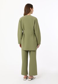 Olive green, lightweight fabric outfit with a loose-fitting long sleeve top and wide-leg pants; features a clean, minimal design.