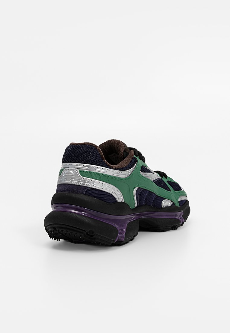 Chaussures de sport vertes et argentées avec une tige en maille et synthétique, semelle noire, amorti violet et caractéristiques de conception distinctes, y compris un col rembourré.