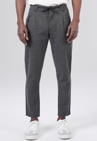 Gray wool blend trousers with a straight leg, pleats, and an adjustable drawstring waist, paired with white sneakers.