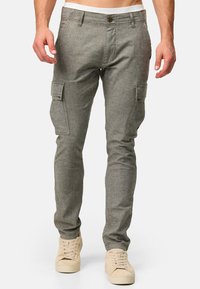 Pantalones cargo grises de corte ajustado, confeccionados en tejido texturizado, con bolsillos laterales con solapa y cierre de botón en la cintura.