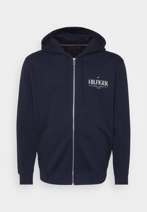 Marineblauwe zip-up hoodie gemaakt van een katoenmix, met een voorzak, trekkoordkap en een witte "HILFIGER NEW YORK" logo. Gladde textuur.