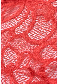 Red lace fabric featuring intricate patterns with open weaves and textured details, showcasing a floral design.