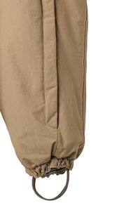 Tan insulated pant leg with gathered cuffs, featuring side seams and an adjustable loop at the hem for securing fit. Smooth texture.