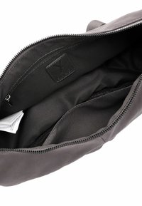 Borsa grigia in pelle con una texture liscia, chiusura con zip e un interno semplice caratterizzato da una fodera in tessuto nero e diverse tasche.